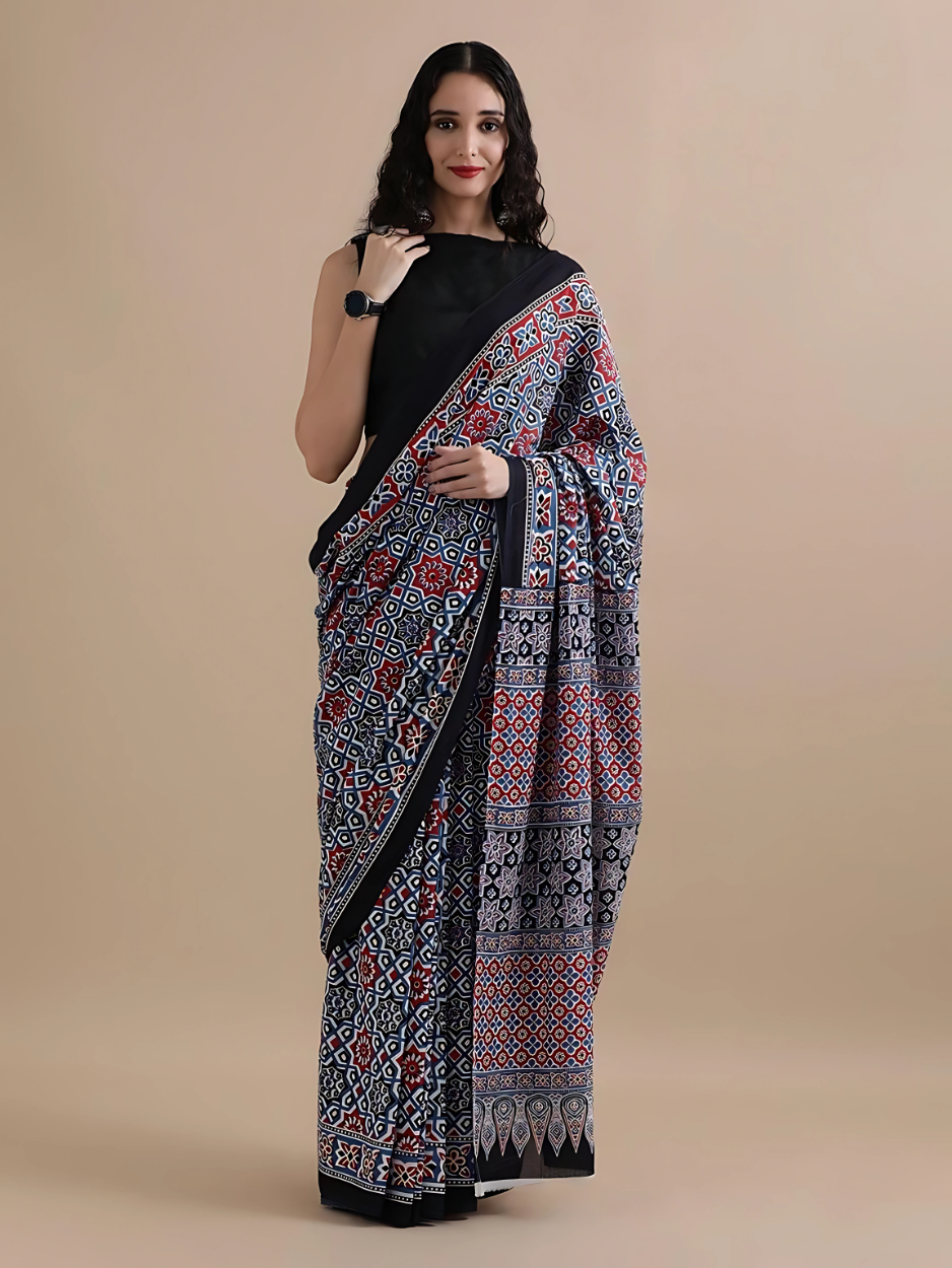Woman wearing a black saree with a colorful pattern on a beige background